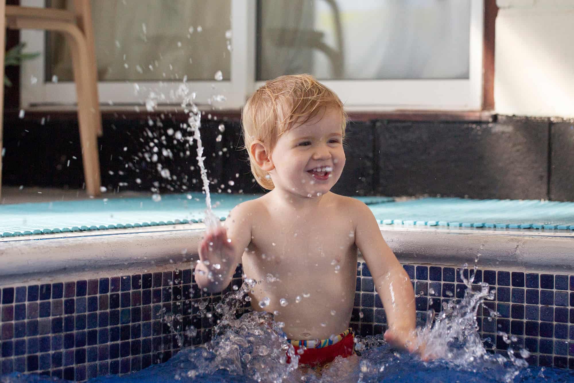 Boy splashing in water using a swim nappy