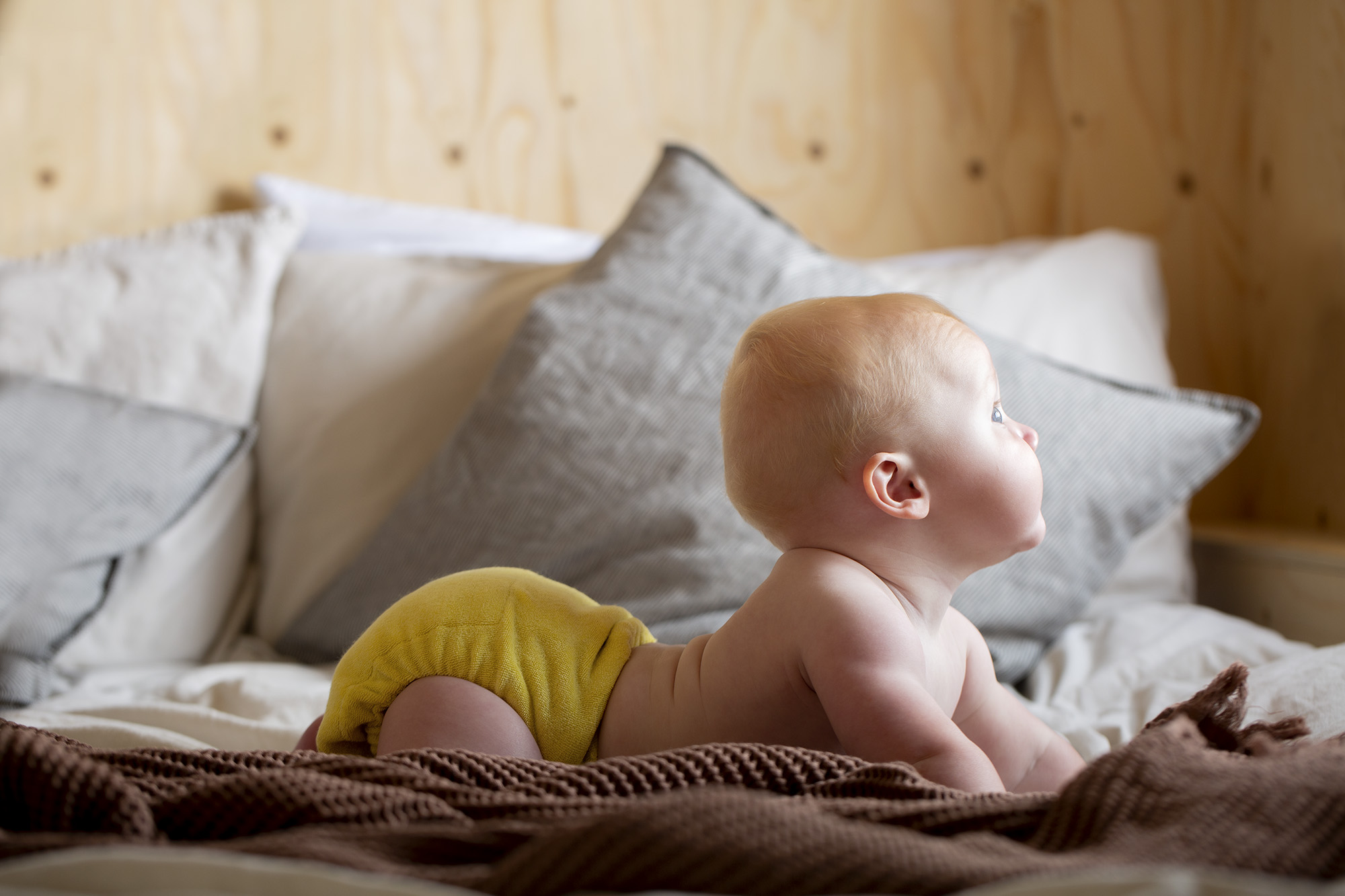 Baby lying down looking out of a window wearing a reusable cloth nappy