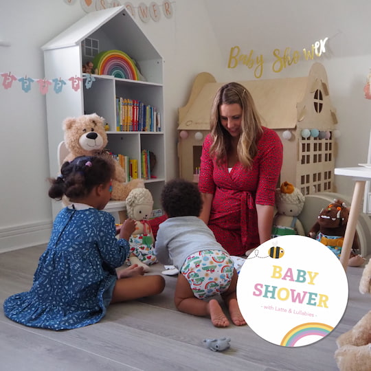 Pamella from Latte and Lullabies in playroom baby shower scene with wooden scandi playhouse in background children wearing sustainable resuable nappies and parent sat watching