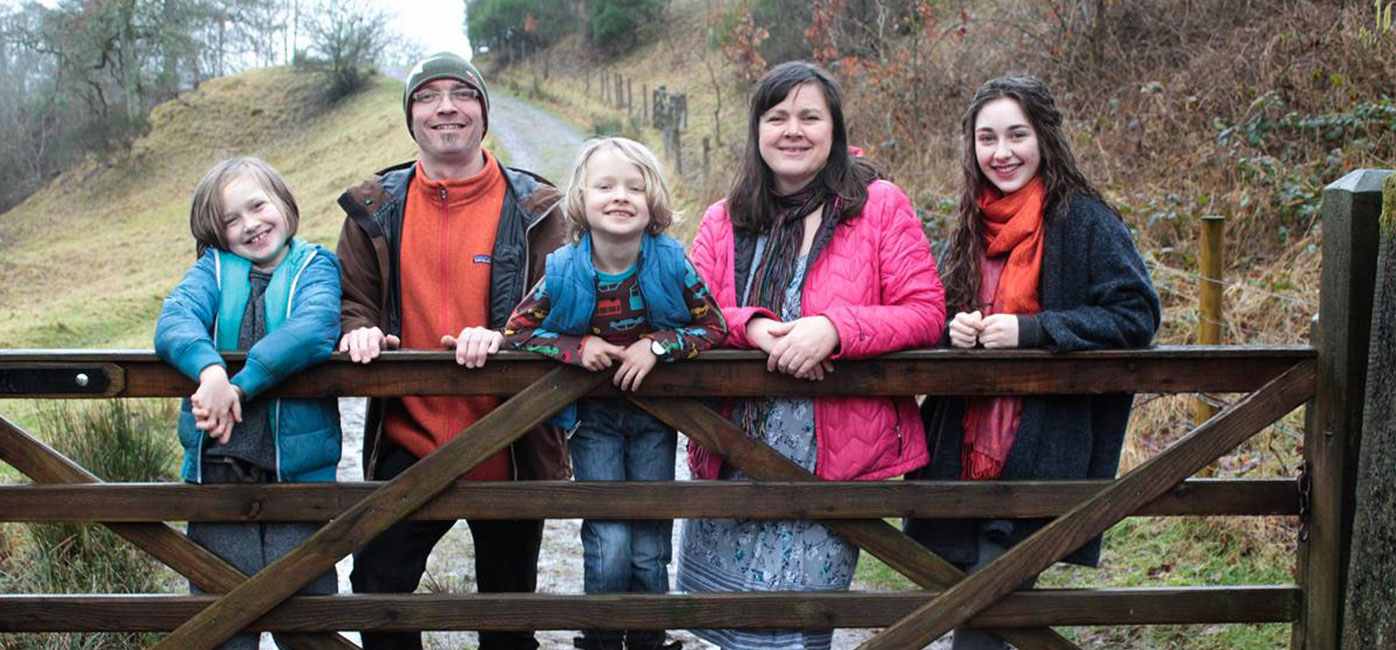 totsbots-founders-family-picture-in-woodland-two-adults-three-children-leaning-on-gate