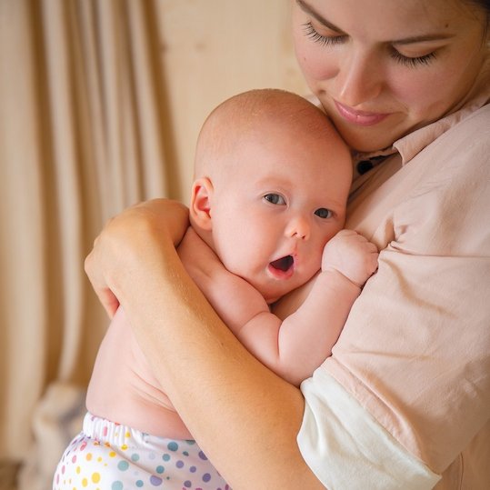 mother-holding-and-cuddling-baby-wearing-reusable-nappy-totsbots